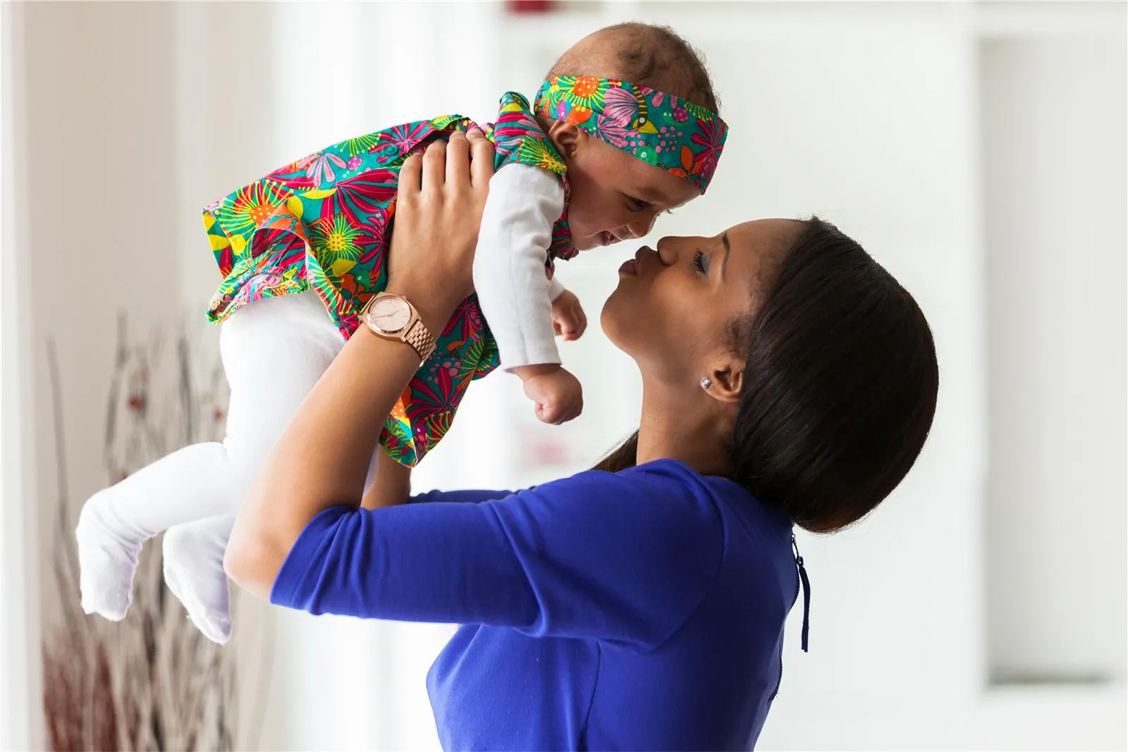 A smiling mother lifting her baby in the air